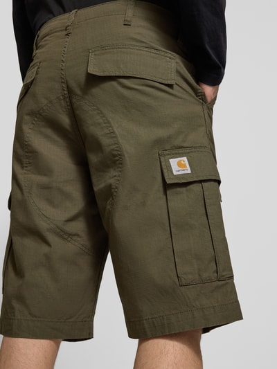 Männermodel trägt Shorts mit Cargotaschen von Carhartt Work In Progress in Olivgrün, Gesäßtaschen, Ganzkörperansicht Rückansicht.