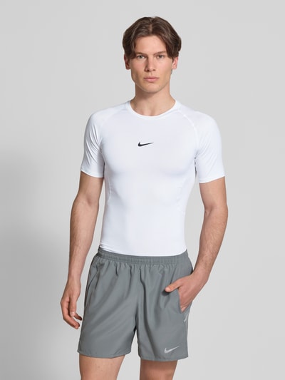 Männermodel trägt T-Shirt mit Logo-Print und Rundhalsausschnitt von NIKE TRAINING, Slim-Fit, Raglanärmel, weiße Farbe, Ganzkörperansicht von vorne. Rückenlänge bei Größe M: 72 cm.