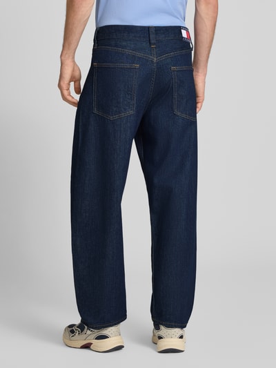 Männermodel trägt dunkelblaue Barrel fit Jeans aus Baumwoll-Mix Modell 'ASHTON' von Tommy Jeans, Herren Barrel Jeans, Ganzkörperansicht Rückansicht.