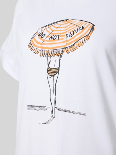 Frauenmodel trägt Oversized Nachthemd mit Motiv-Print Modell 'Sommerliebe' von LOUIS & LOUISA aus Reiner Baumwolle, weiß mit orangem und schwarzem Print, Rundhalsausschnitt, Ärmel mit Aufschlag, Nahaufnahme Oberkörper.