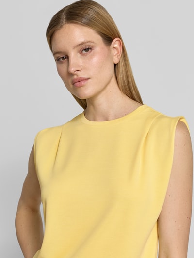 Kobiece modelka nosi Top mit Rundhalsausschnitt und Kappärmeln von Jake*s Collection, mieszanka modalu, prosty krój, żółty kolor, okrągły dekolt, krótkie rękawy, długość tyłu w rozmiarze S: 54 cm, zbliżenie na górną część ciała z przodu.