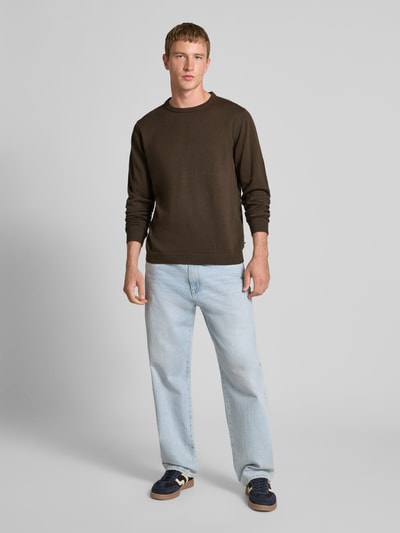 Męski model ma na sobie Longsleeve mit Rundhalsausschnitt od Jack & Jones z bawełny, prosty krój, detal z logo, prążkowane wykończenia, długość tyłu 72 cm, długość rękawów 71 cm, widok całej sylwetki z przodu.
