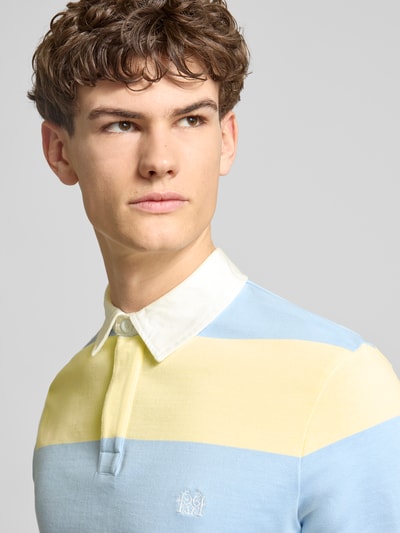 Männermodel trägt Regular Fit Poloshirt mit Rugby-Streifen und Logo-Bestickung von REVIEW, pastellblaue und gelbe Blockstreifen, reine Baumwolle, Nahaufnahme Oberkörper.