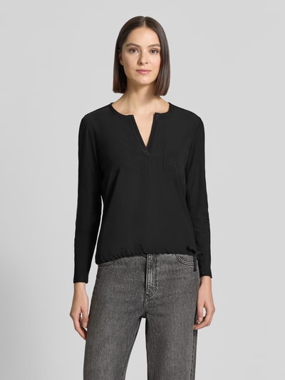 Frauenmodel trägt Regular Fit Bluse mit Brusttaschen von monari, schwarze Farbe, Ziersteinbesatz, Tunika-Ausschnitt, Langarm, Ganzkörperansicht von vorne.