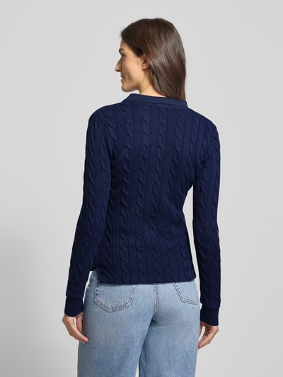 Vrouwenmodel draagt Strickpullover mit Zopfmuster und Polokragen van Polo Ralph Lauren in donkerblauw, puur katoen, slim fit, kabelpatroon, labelstitching, polokraag, knoopsluiting, ruglengte maat S 63 cm, mouwlengte maat S 66 cm, volledig beeld achterkant.