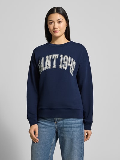 Frauenmodel trägt Sweatshirt mit Label-Print und Rundhalsausschnitt von Gant, reine Baumwolle, Relaxed-Fit, dunkelblau, Ganzkörperansicht von vorne.