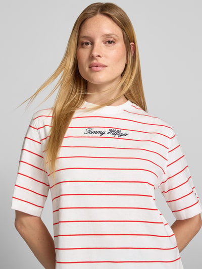 Frauenmodel trägt Regular Fit T-Shirt aus reiner Baumwolle von Tommy Hilfiger, weiß mit roten Streifen, Schriftzug auf Brust, Nahaufnahme Oberkörper, Damen T-Shirt von Tommy Hilfiger.
