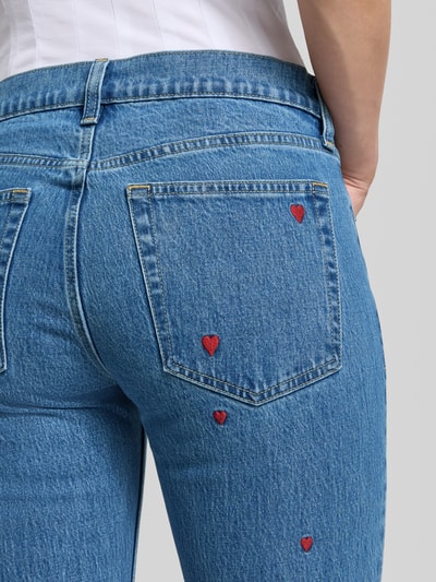 Vrouwenmodel draagt Relaxed Straight Fit Jeans met Stickerei van GAP, blauwe denim, mix van katoen en elastaan, geborduurde rode harten, 5-pocketmodel, knoop- en ritssluiting, bandwijdte maat 27/32: 39 cm, binnenbeenlengte: 79 cm, detailopname rugaanzicht.