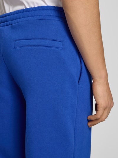 Mannenmodel draagt sweatpants met elastische band van REVIEW, materiaalmix met katoen, relaxed fit, achterzak, detailopname heup.