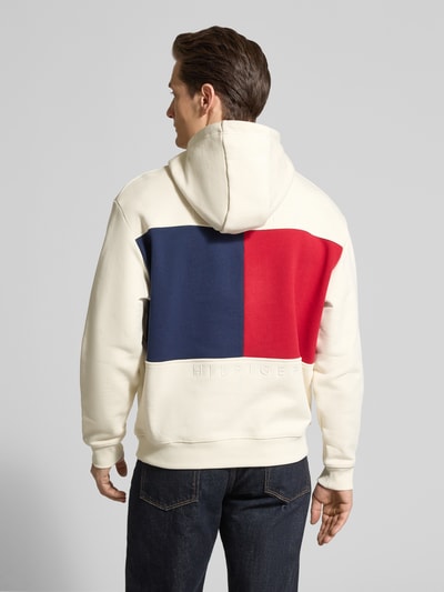 Männermodel trägt Regular Fit Hoodie aus reiner Baumwolle von Tommy Hilfiger, cremefarben mit Logo-Detail, Ganzkörperansicht Rückansicht.