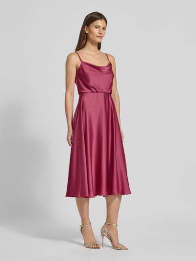 Frauenmodel trägt Cocktailkleid mit Wasserfall-Ausschnitt von Jake*s Cocktail in Satin, taillierte Passform, knielang, Ganzkörperansicht von vorne.