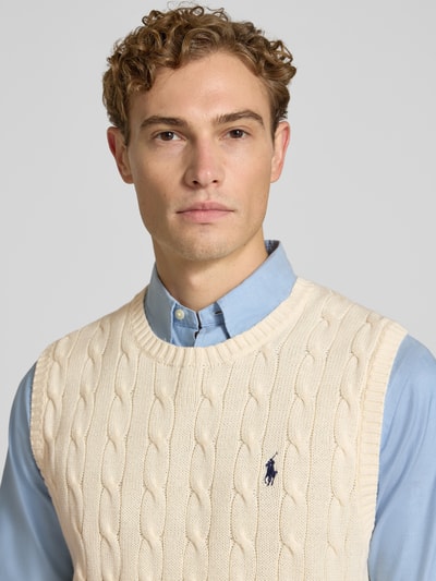 Männermodel trägt Regular Fit Pullunder aus reiner Baumwolle von Polo Ralph Lauren in Creme mit Zopfmuster, Nahaufnahme Oberkörper.