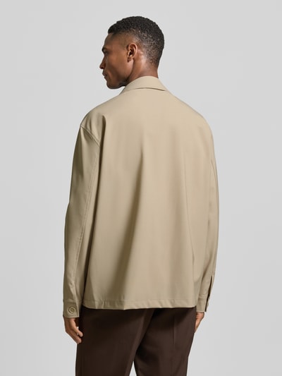Männermodel trägt Hemdjacke aus Schurwoll-Elasthan-Mix mit Brusttasche von CRUNA in Beige, Regular-Fit, glatte Textur, Rückenlänge 74 cm, Ganzkörperansicht Rückansicht.