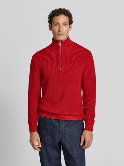 Männermodel trägt Slim Fit Strickpullover aus reiner Baumwolle mit Troyer-Kragen von MCNEAL, kräftiges Rot, gerippte Textur, Ganzkörperansicht von vorne