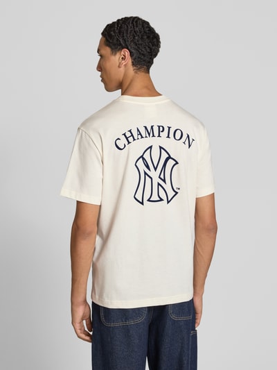 Männermodel trägt Relaxed Fit T-Shirt aus reiner Baumwolle von Champion, weiß mit Statement-Print und Label-Stitching, Ganzkörperansicht Rückansicht. Rückenlänge bei Größe M: 70 cm