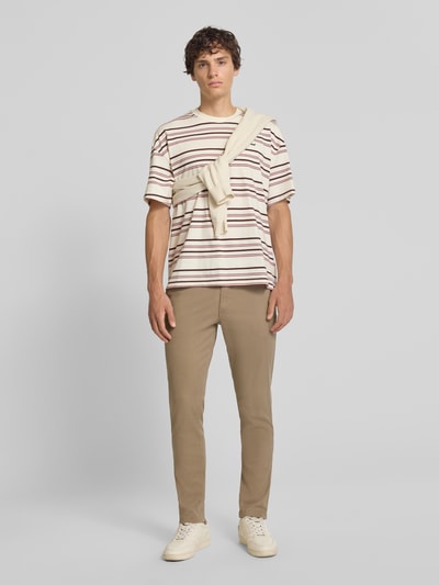 Męski model nosi spodnie Slim Fit Hose mit Gesäßtaschen Modell 'MARCO' von Jack & Jones, mieszanka bawełny i elastanu, beżowy, krój slim fit, kieszenie z tyłu, Szerokość w rozmiarze 32/32: 43 cm, Długość wewnętrzna nogawki w rozmiarze 32/32: 77 cm, Ganzkörperansicht von vorne.