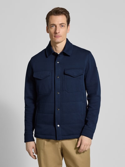 Männermodel trägt Regular Fit Sweatjacke aus Baumwoll-Mix von Tommy Hilfiger, unifarben dunkelblau, Druckknopfleiste, Ganzkörperansicht von vorne.