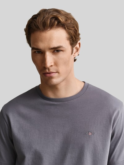 Männermodel trägt Regular Fit T-Shirt aus reiner Baumwolle von GANT, Herren T-Shirt in Grau mit glatter Baumwoll-Textur, Nahaufnahme Oberkörper.