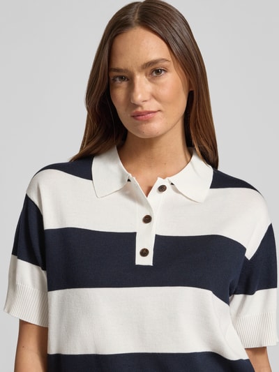 Frauenmodel trägt Regular Fit Poloshirt aus Viskose-Mix Modell 'LULS' von ICHI, breite Streifen in Dunkelblau und Weiß, Nahaufnahme Oberkörper. Damen Poloshirt, Strick-Optik, Rückenlänge 58 cm, Ärmellänge 21 cm.