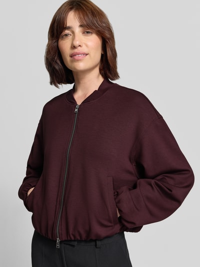Frauenmodel trägt Regular Fit Sweatjacke aus Viskose-Mix von Brax in dunklem Bordeauxrot, glatte Struktur, Ganzkörperansicht von vorne.