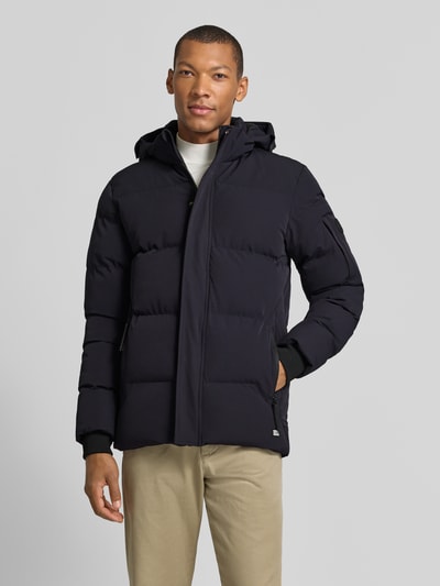 Männermodel trägt Regular Fit Steppjacke mit Reißverschlusstaschen Modell 'JAXHAM' von Cars Jeans in Schwarz, Material-Mix, Ganzkörperansicht von vorne.