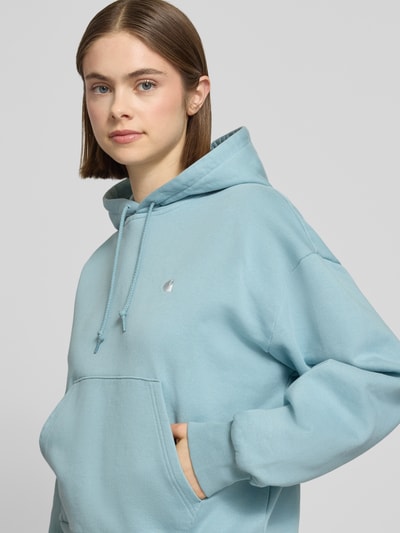 Frauenmodel trägt Hoodie mit Label-Stitching und Känguru-Tasche von Carhartt Work In Progress, Reine Baumwolle, Relaxed-Fit, Nahaufnahme Oberkörper.