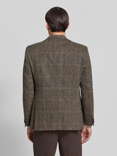 Männermodel trägt Sakko mit Pattentaschen Modell 'Theo' von Carl Gross in braun kariertem Muster, Reine Viskose, Ganzkörperansicht Rückansicht.