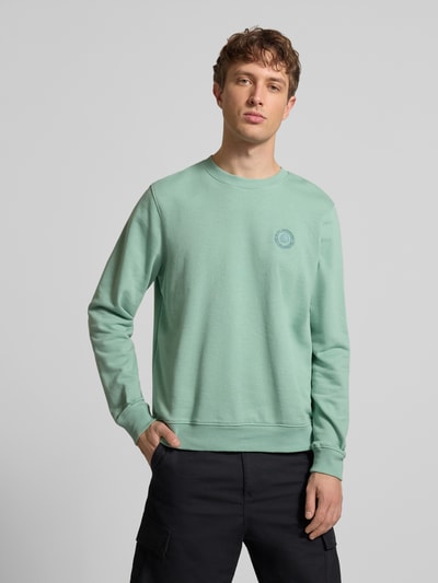 Männermodel trägt Regular Fit Pullover mit Logo-Stitching Modell 'Kane' von Blend in Mintgrün, Baumwoll-Mix, Rundhalsausschnitt, Ganzkörperansicht von vorne.