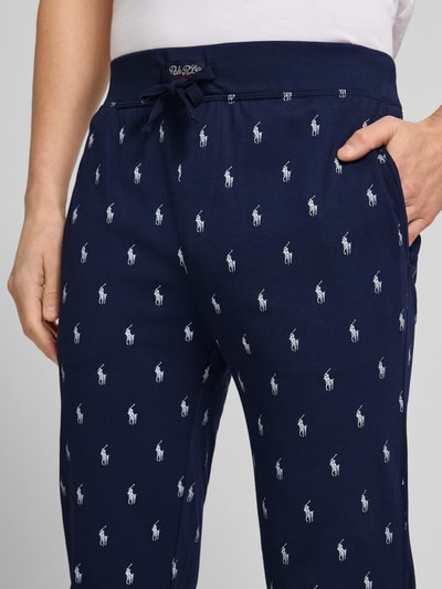 Männermodel trägt Sweathose mit Allover-Logo-Print von Polo Ralph Lauren in donkerblauw, katoen, losse pasvorm, detailopname heup.