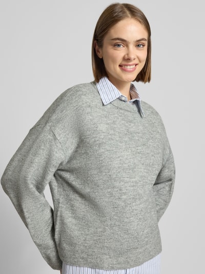 Modelka nosi szary sweter z okrągłym dekoltem Relaxed Fit model 'SIMONI' od ONLY, damski sweter, neutralne kolory, zbliżenie górnej części ciała.