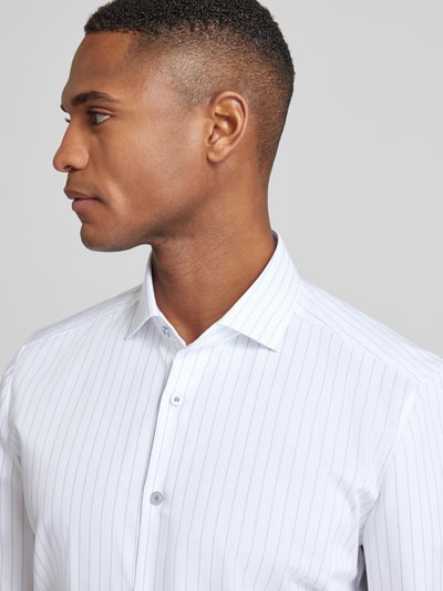 Männermodel trägt Slim Fit Businesshemd aus Baumwoll-Mix mit Kentkragen von OLYMP, weiß mit feinen Streifen, Nahaufnahme Oberkörper. Elastischer Baumwoll-Mix, Langarm, Sportmanschetten, durchgängige Knopfleiste.