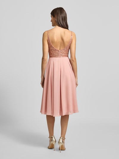 Frauenmodel trägt Regular Fit Minikleid mit Ziersteinbesatz von Hey Kyla, semitransparent, tiefer V-Ausschnitt, Ganzkörperansicht Rückansicht.