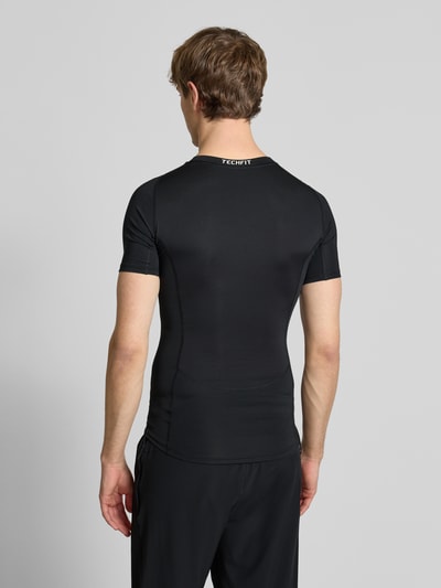 Männermodel trägt T-Shirt mit Label-Print von adidas Training in Schwarz, Slim Fit, Material-Mix mit Stretch, Ganzkörperansicht Rückansicht.