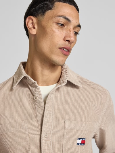 Männermodel trägt Regular Fit Cordhemd mit Logo-Patch von Tommy Jeans in Beige, grobe Cordstruktur, Nahaufnahme Oberkörper, Herren Freizeithemd von Tommy Jeans