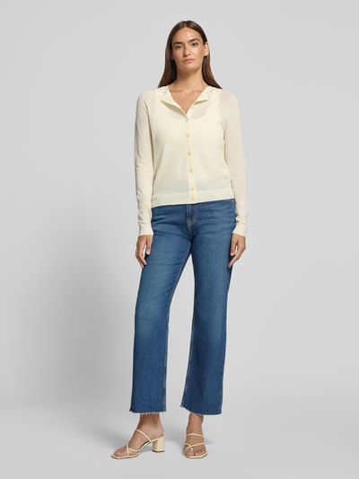 Frauenmodel trägt Relaxed Fit Strickjacke aus reiner Schurwolle Modell 'FONAMI' von BOSS in Creme, kombiniert mit Jeans, Ganzkörperansicht von vorne. Damen Strickjacke.