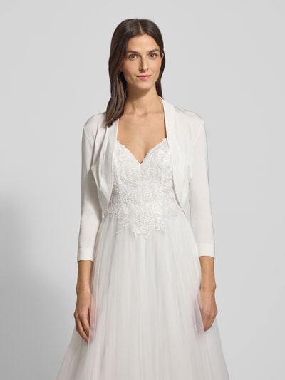 Frauenmodel trägt Bolero mit Schalkragen von Jake*s Cocktail aus schimmernder Viskosemischung, offene Vorderseite, Dreiviertel-Ärmel, gerippte Abschlüsse, Rückenlänge bei Größe 36: 39 cm, Ganzkörperansicht von vorne.