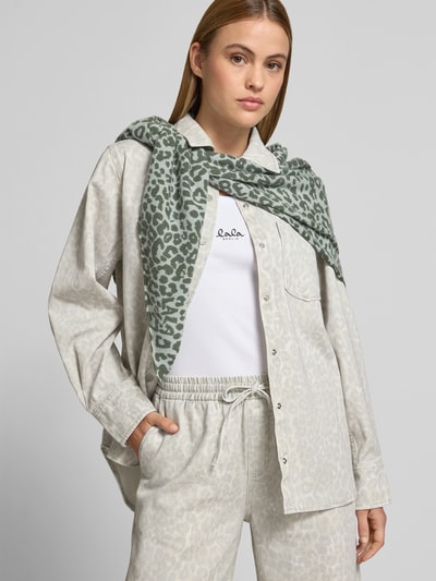 Frauenmodel trägt Kaschmirtuch aus reinem Kaschmir von Lala Berlin mit Allover-Animal-Print, Strick-Optik, Logo-Detail, Dreiecksform, Ganzkörperansicht von vorne.