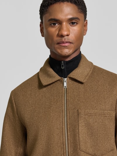 Männermodel trägt Jacke mit Brusttasche und Kentkragen Modell 'ROLFSTED' von Casual Friday in Braun, Nahaufnahme Oberkörper, gerader Schnitt, sichtbarer Reißverschluss, KI-modifiziertes Bild.
