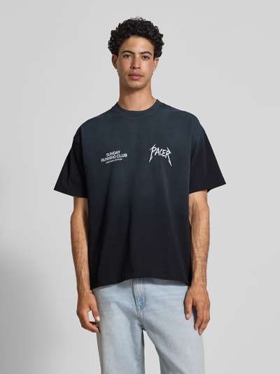 Männermodel trägt schwarzes T-Shirt mit weißem Statement-Print, Boxy Fit, reine Baumwolle, SRC® Pacer von ANOTHER COTTON LAB, Nahaufnahme Oberkörper