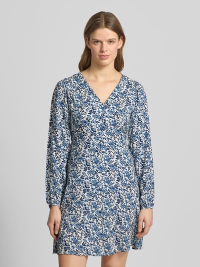 Frauenmodel trägt tailliertes Freizeitkleid aus reiner Viskose Modell 'EVIDA' von Only, Optik: Allover-Muster, Mini-Länge, V-Ausschnitt, Knopfleiste, Langarm, Ballonärmel, Ärmelabschluss mit Knopf und Öse, Textur weich, Farben Blau und Weiß, Ganzkörperansicht von vorne.