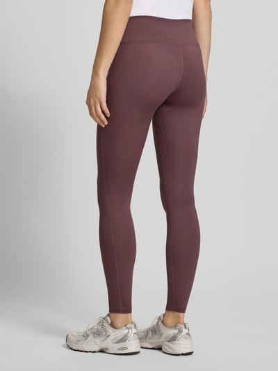 Frauenmodel trägt Leggings mit Logo von NIKE TRAINING, Material-Mix mit Stretch-Anteil, körpernahe Passform, elastischer Bund, Ganzkörperansicht Rückansicht.