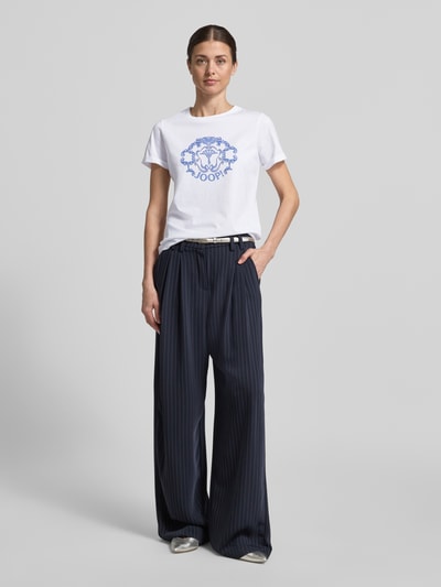 Vrouwenmodel draagt Regular Fit T-shirt met strass-steentjes model 'Tulya' van JOOP! van puur katoen, logoprint, ronde hals, ruglengte bij maat 36: 62 cm, Ganzkörperansicht von voren.