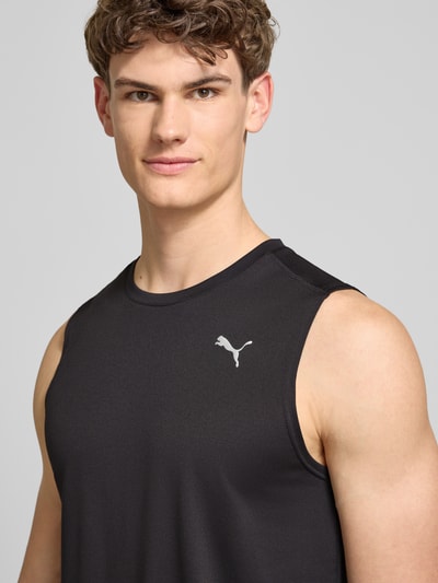 Männermodel trägt schwarzes Top mit Logo und Rundhalsausschnitt von PUMA PERFORMANCE, glatte Textur, Nahaufnahme Oberkörper.