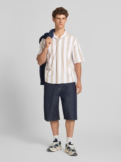 Männermodel trägt Relaxed Fit Freizeithemd aus reiner Baumwolle Modell 'TES' von Only & Sons mit Optik:Allover-Muster, gestreift, Knopfleiste einreihig, Reverskragen, Kurzarm, beige-weiß, strukturierte Baumwolle, Ganzkörperansicht von vorne.