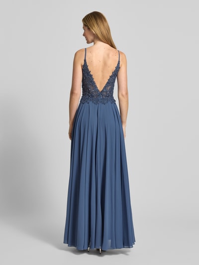 Frauenmodel trägt Abendkleid mit Pailletten- und Ziersteinbesatz von Mascara in Blau mit floralem Spitzenbesatz, Chiffon, Rückansicht Ganzkörperansicht. Semitransparente Optik, Herz-Ausschnitt, ärmelloses Design mit Spaghettiträgern, taillierte Passform, Nahtreißverschluss, blickdichter Unterrock, Rückenlänge bei Größe 36: 140 cm, Brustweite 40 cm.