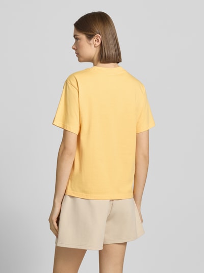 Modelka kobieta ma na sobie Regular Fit T-Shirt mit Logo-Print od adidas Sportswear w kolorze żółtym z krótkim rękawem, bawełna, krój regular fit, długość tyłu w rozmiarze S: 59 cm, widok całej sylwetki z tyłu.
