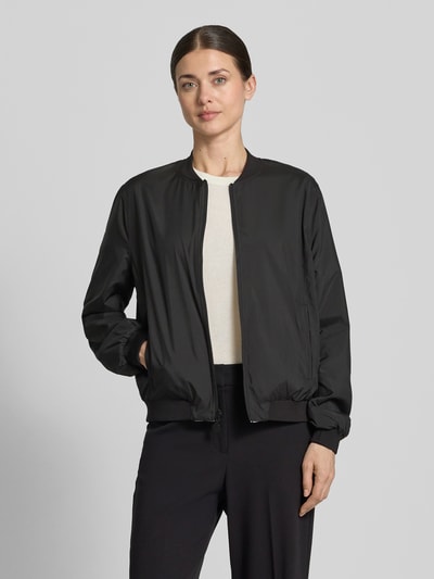 Frauenmodel trägt Blouson mit Eingrifftaschen Modell 'SUZY BLUE' von Frieda & Freddies im Material-Mix mit Stretch-Anteil, Loose-Fit, Farbe Schwarz, kurzer Stehkragen, Reißverschluss, elastische Abschlüsse, Label-Detail, Ganzkörperansicht von vorne.