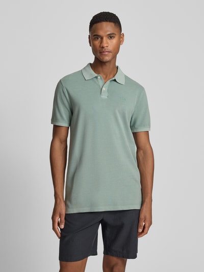 Männermodel trägt Slim Fit Poloshirt mit Label-Stitching von GAP in Mintgrün, Baumwoll-Elasthan-Mix, Knopfleiste, Ganzkörperansicht von vorne.