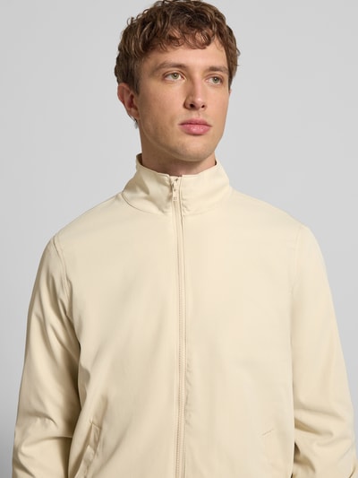 Männermodel trägt Regular Fit Jacke mit Stehkragen Modell 'Hefi' von Blend in Beige, glatte Baumwolle, Nahaufnahme Oberkörper, Herrenjacke, Reißverschluss, Eingrifftaschen, elastische Abschlüsse, Maße für Größe M.