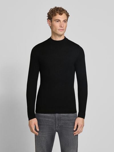 Männermodel trägt schwarzen Slim Fit Longsleeve aus reiner Schurwolle Modell 'Arwon' von DRYKORN, Stehkragen, Ganzkörperansicht von vorne.